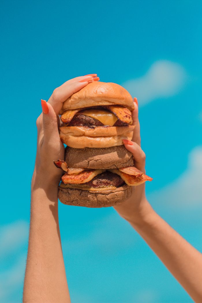 Tasty double cheeseburger with bacon against a vibrant sky, perfect for food photography.