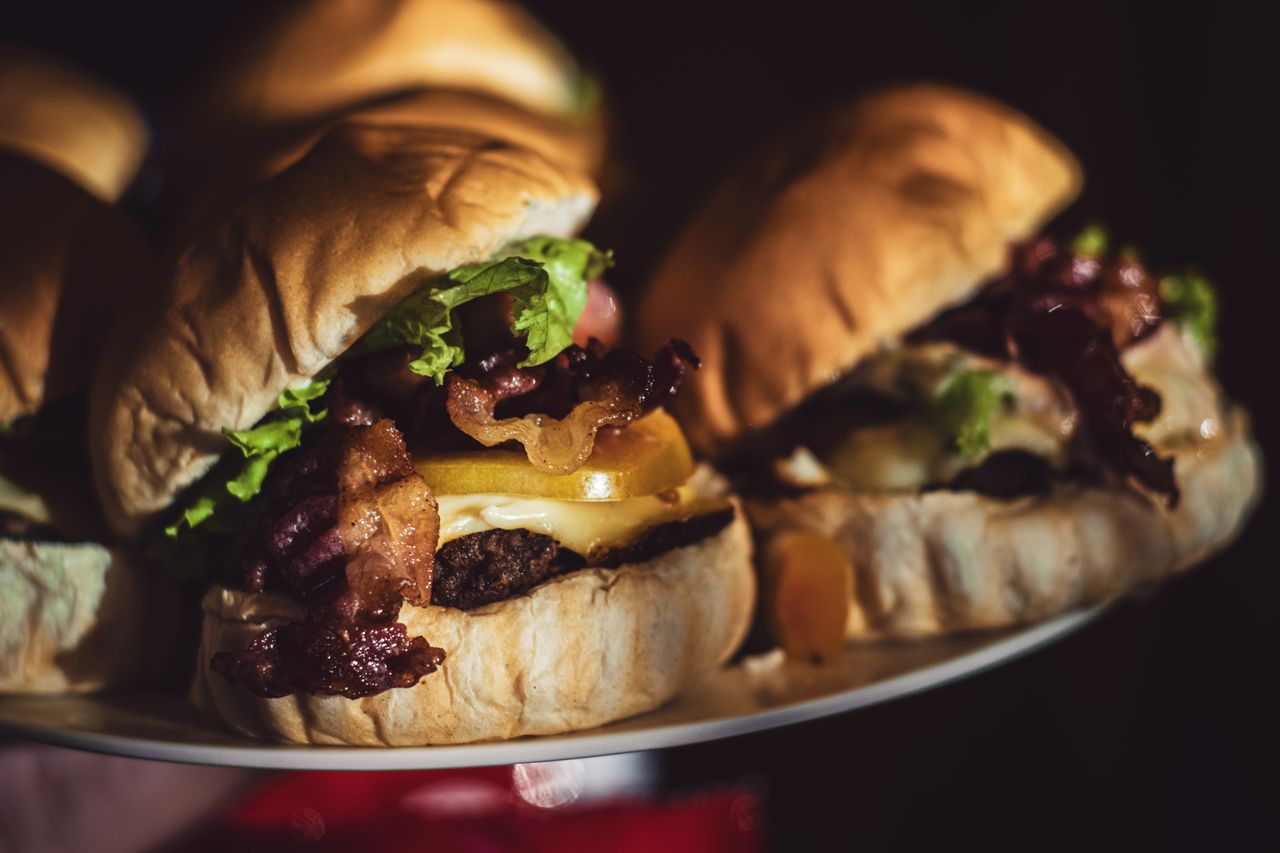 Mouth-watering burgers stacked with bacon, cheese, and lettuce captured in rich detail.